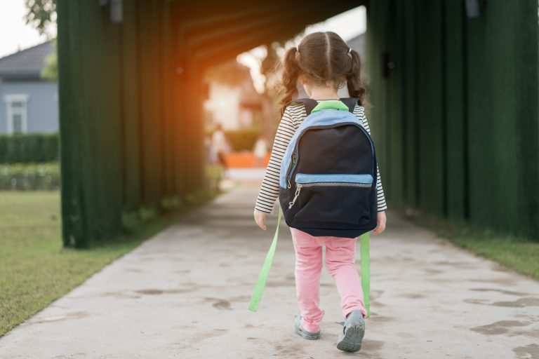 rear-view-girl-with-backpack-walking-footpath